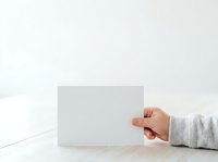 Hand holding blank white card on wooden surface with minimalist background for branding, marketing, and business presentation mockups.