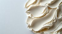 Elegant cream-colored meringue waves create soft flowing texture against light background, showcasing delicate culinary artistry and minimalist food styling.