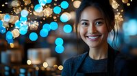 Young Southeast Asian woman smiling at camera wearing dark blazer against blurred bokeh lights background. Corporate portrait for business, professional networking, leadership and career development.