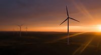 Wind turbines generating clean renewable energy at golden sunset with dramatic sky and rolling hills landscape for sustainable power concepts.