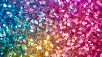 Vibrant rainbow gradient pattern created with sparkling crystal fragments and glitter pieces arranged in colorful spectrum from blue and turquoise to pink and magenta.