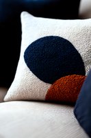 Modern decorative throw pillow with geometric circle pattern in navy blue and rust orange on white textured fabric, showcasing contemporary minimalist design.