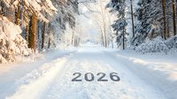 Snowy forest path with number 2026 written in snow, sunlight streaming through winter trees creating magical atmosphere along white covered trail.