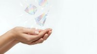 Open hand releasing colorful geometric shapes and light particles against white background, isolated design element for business, technology, creativity, and innovation concepts.