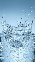 Dynamic water splash with crown formation and bubbles against blue gradient background for refreshing beverage and hydration concepts.