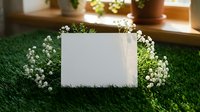 Blank white card surrounded by delicate baby's breath flowers on green grass surface with warm natural lighting for spring greeting designs.