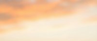 Soft peachy and golden clouds drift across a serene sky during golden hour, creating a tranquil atmosphere suitable for backgrounds, wellness content, and inspirational designs.