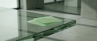 Transparent green glass sheets stacked on modern surface with clean geometric lines and reflective properties for architectural and design applications.