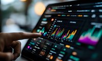 Financial analyst pointing at colorful stock market data charts on digital tablet screen with blurred background.