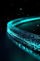 Glowing turquoise light trail with sparkling particles against dark background creates magical effect, curved path of luminescent energy streaming through space.