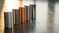 Cylindrical metal samples arranged in a row on a reflective surface, showcasing various finishes and textures for material selection and industrial design reference.