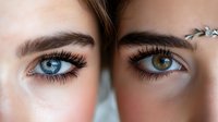 Close up macro shot of two different colored eyes with long eyelashes and defined eyebrows showing heterochromia, one blue and one brown eye. Beauty concept.