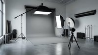 Professional photo studio interior with gray backdrop, softbox lights, reflector, and camera on tripod, ready for a commercial shoot.