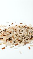 Mixed grain rice pile with white, brown, and wild rice varieties scattered on isolated white background, suitable for food packaging and culinary design projects.