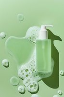 Green cosmetic bottle with white pump dispenser surrounded by foam bubbles and shadow on monochromatic mint background for skincare product presentation.