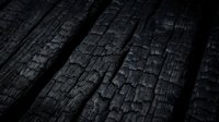 Dark charred wooden planks with cracked burnt texture showing fire damage and weathered surface patterns for rustic design backgrounds.