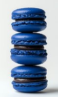 Stack of three blue macarons with dark chocolate filling on white background, French pastry dessert for bakery menu and culinary advertising.