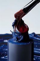 Makeup brush with red liquid paint creating dynamic splash effect against blue water drops on dark podium, artistic cosmetic still life on light background.
