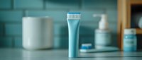 Blue electric toothbrush standing upright on bathroom counter with blurred personal care products in background, modern dental hygiene concept.