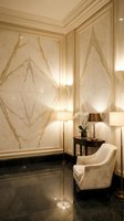 Luxury hotel lobby corner with marble wall panels, elegant armchair, side table with orchid, warm lighting creating sophisticated hospitality interior design.
