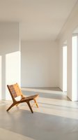 Modern minimalist interior with wooden lounge chair in sunlit room featuring clean white walls and natural light streaming through windows.