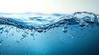 Dynamic underwater wave with air bubbles and rippling surface captured in vibrant blue tones, showing fluid motion and transparency. Suitable for environmental themes.