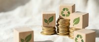 Stacked coins with wooden blocks featuring green leaf and recycling symbols representing sustainable investment, eco-friendly finance, and environmental responsibility for business concepts.