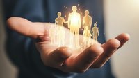 Businessman hands holding glowing human figures representing team leadership, community support, and corporate responsibility in modern office setting.