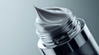 Metallic silver cosmetic cream swirl on luxury skincare container top, elegant premium beauty product packaging against soft gray background.