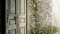 Weathered wooden door with peeling paint against ancient stone wall creates rustic Mediterranean atmosphere for vintage home decor and architectural design.