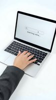 Person using laptop computer with search bar displaying searching online message on screen for internet browsing and web research activities.