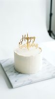 Minimalist white birthday cake with gold topper and lit candle on marble board, elegant celebration dessert for party and event design.