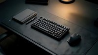 Modern minimalist workspace with mechanical keyboard, mouse and notebook on dark desk under warm lamp lighting for productivity and gaming setup.