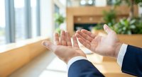 Business professionals reaching hands together in modern office environment showing teamwork collaboration and partnership agreement.