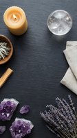 Spiritual wellness flatlay with amethyst crystals, candle, crystal ball, sage, palo santo, and lavender on dark slate background.