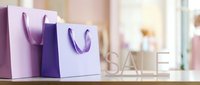 Purple and lavender shopping bags with SALE sign on wooden table in bright boutique, retail discount promotion concept.