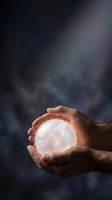 Male hands holding glowing crystal ball with luminous orb against blurred dark background. Suitable for spirituality, fortune telling, magic, and mystical concepts.