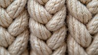 Close up macro view of natural beige cotton rope braided in decorative pattern showing detailed texture of woven fibers and knots for nautical design.