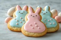 Adorable Easter bunny sugar cookies decorated with pastel pink and blue royal icing, featuring cute kawaii faces and polka dot details on rustic gray background.