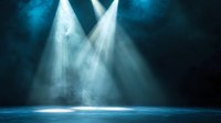 Dramatic stage spotlights pierce through atmospheric smoke creating ethereal beams against dark turquoise background, illuminating empty performance space.