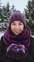 Young Caucasian woman in purple knit hat and scarf holding amethyst crystal in snowy winter forest setting with evergreen trees in background.