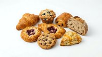 Assorted fresh baked pastries and bread rolls including croissants, muffins, and fruit danish on white background for bakery and food design.