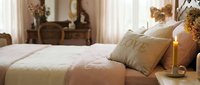 Romantic vintage bedroom with soft pink bedding, love pillow, and glowing candle, creating a cozy and elegant atmosphere for rest and romance.