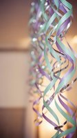 Colorful party streamers in purple and mint green hanging and curling with warm bokeh lights creating festive celebration atmosphere for events and holidays.