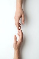 Two hands reaching toward each other in helping gesture on white background symbolizing support, connection, teamwork and assistance in business or personal relationships.