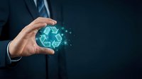 Businessman hand holding glowing recycling symbol with digital particles on dark background representing environmental sustainability and green business practices.