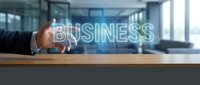 Professional businessman hand touching glowing business text hologram in modern office environment for corporate strategy and digital transformation concepts.