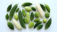 Fresh bitter melon and bitter gourd vegetables arranged on white background, showcasing green organic produce for healthy cooking and traditional cuisine.