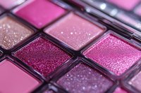 Macro shot of pink and burgundy glittery eyeshadow palette showing shimmering powder texture and sparkles in makeup cosmetics for beauty and glamour.
