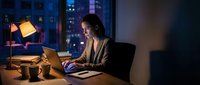 Professional businesswoman working late at night in modern office with city skyline view, using laptop for overtime project deadlines and productivity.